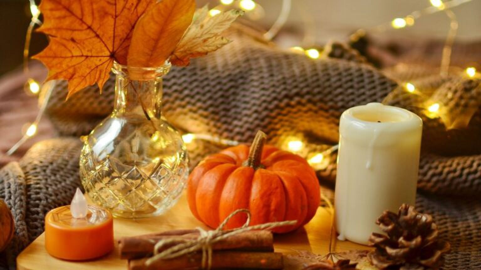 Plateau waar een pompoen, kaars en kaneelstokjes op staan.