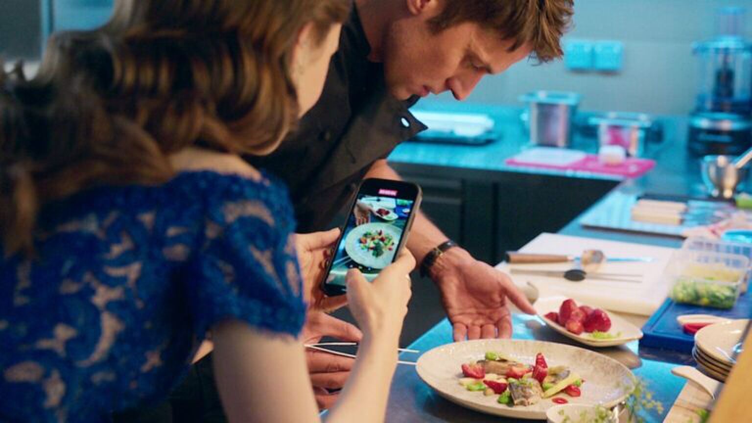 Een jonge vrouw maakt een foto van het gerecht dat haar vriend heeft gemaakt.