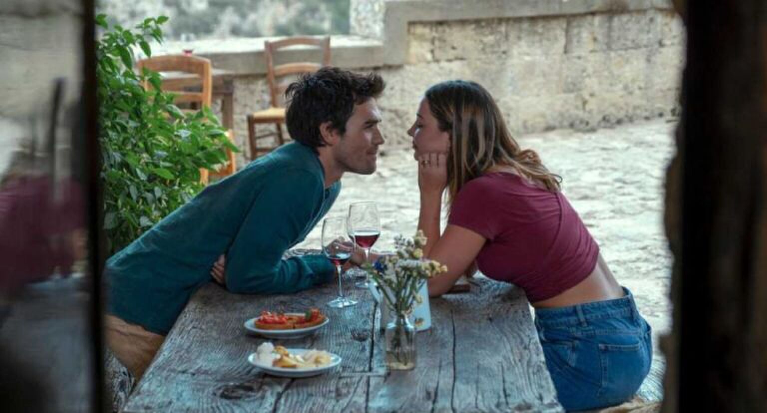 Een jongen en een meisje kijken verliefd naar elkaar over een tafel.