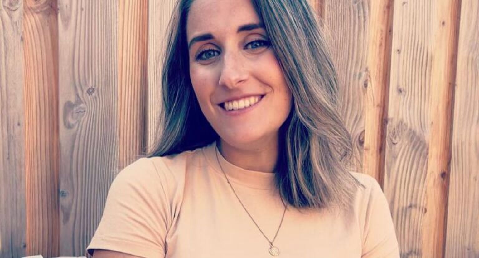 Vrouw kijkt lachend in de camera.