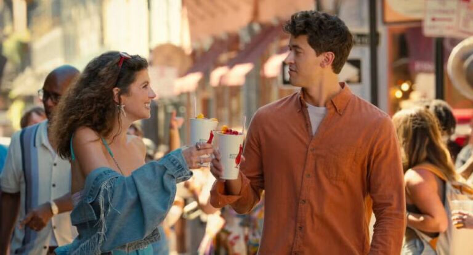 Jongen en meisje lopen samen door een straat en drinken een smoothie.
