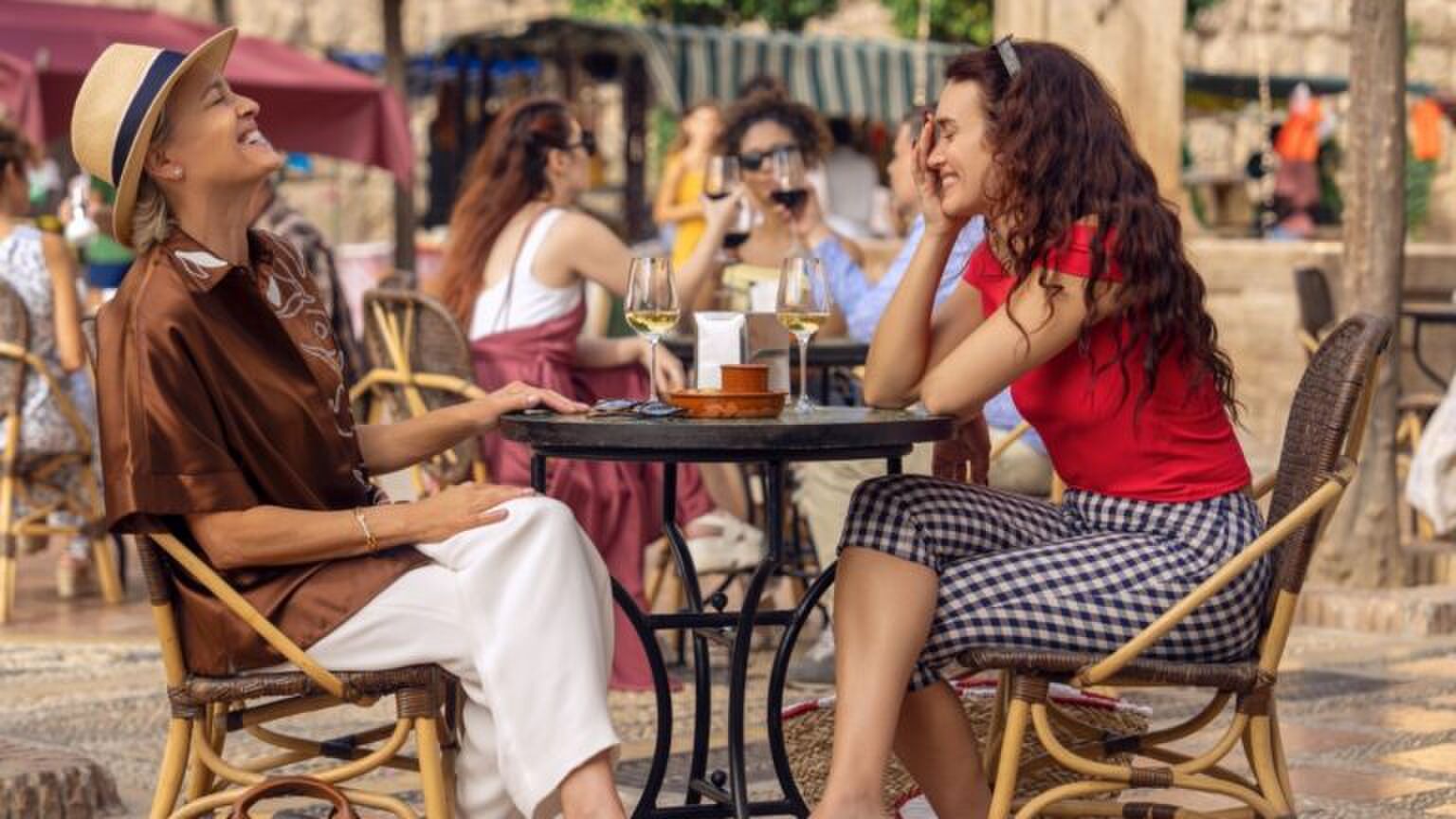 Twee vrouwen zitten samen lachend aan tafel.