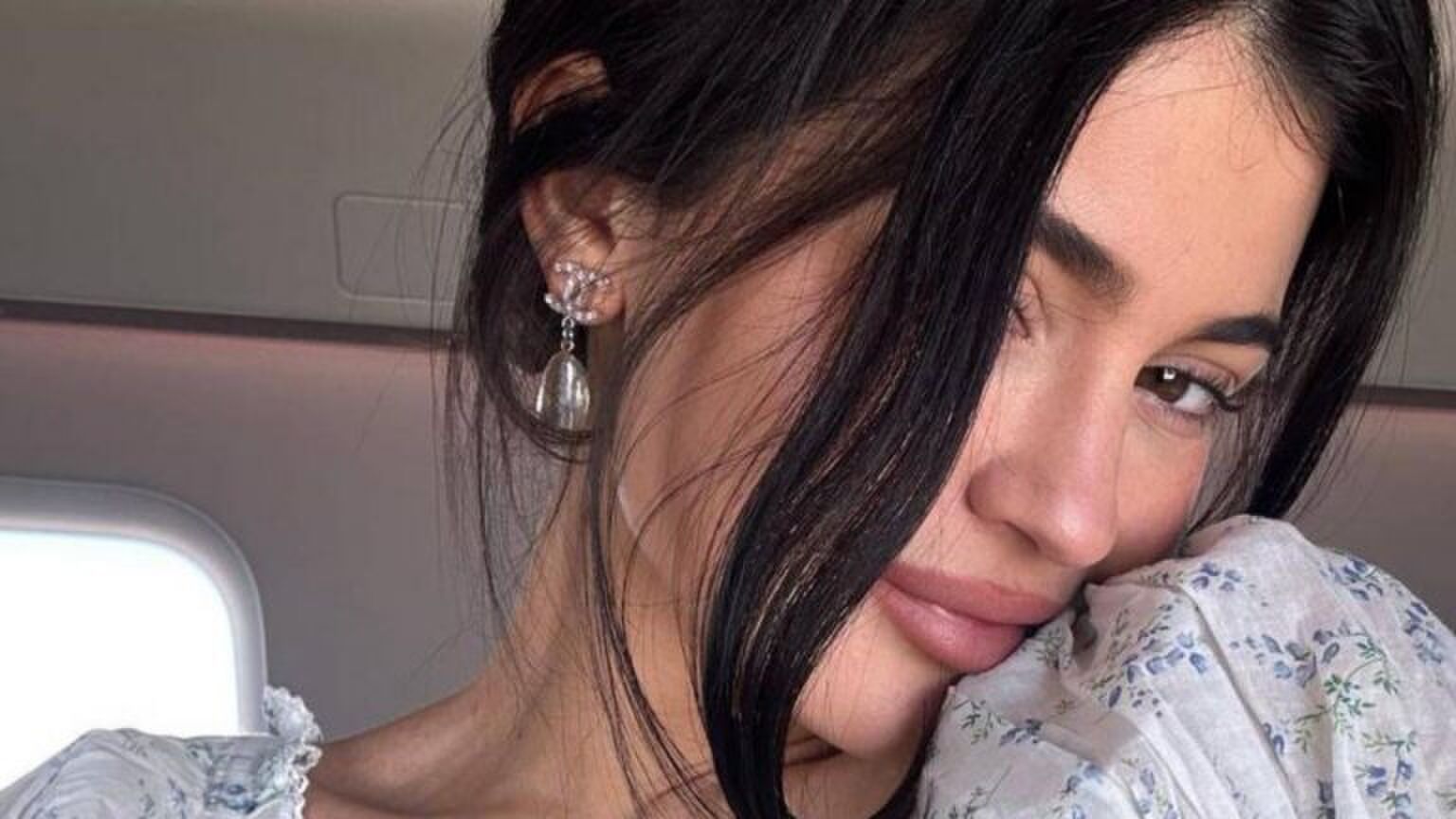 Vrouw kijkt schattig. Ze laat haar oorbel zien.