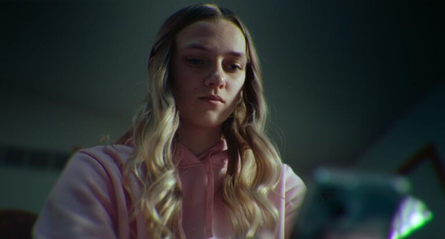 Meisje kijkt angstig naar haar telefoon.