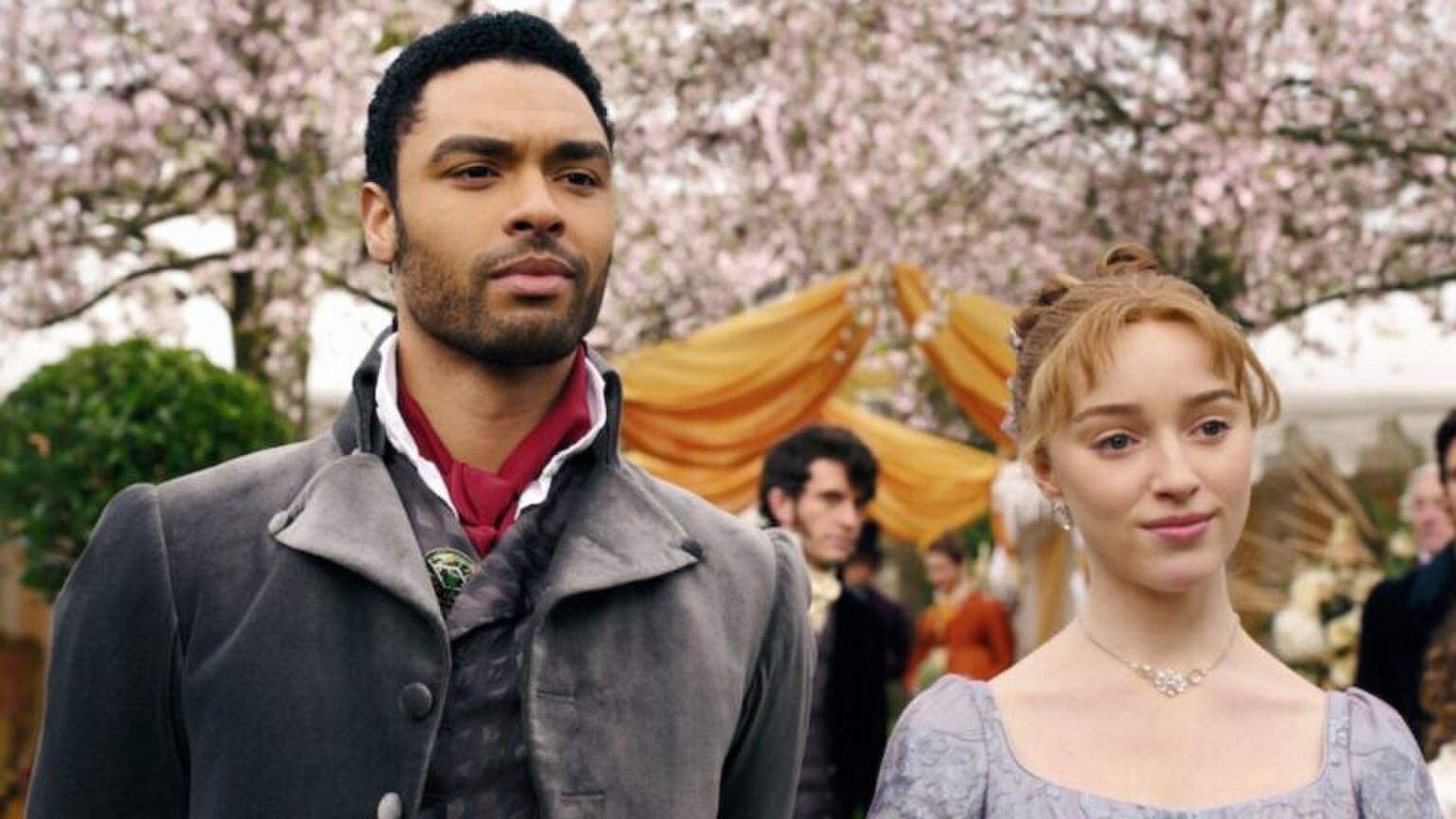 Twee personages uit Bridgerton staande voor een achtergrond.