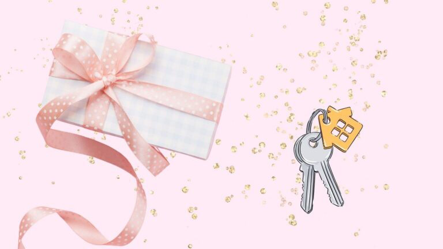 Een cadeautje en een huissleutel voor een roze glitterachtergrond