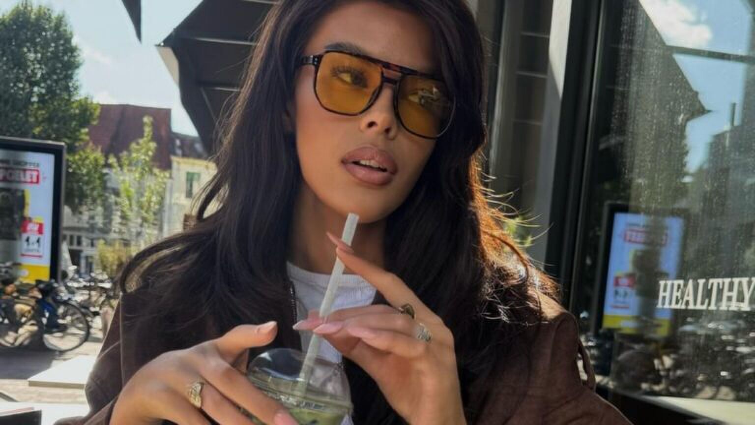 Vrouw poseert met haar drankje. Ze kijkt opzij.