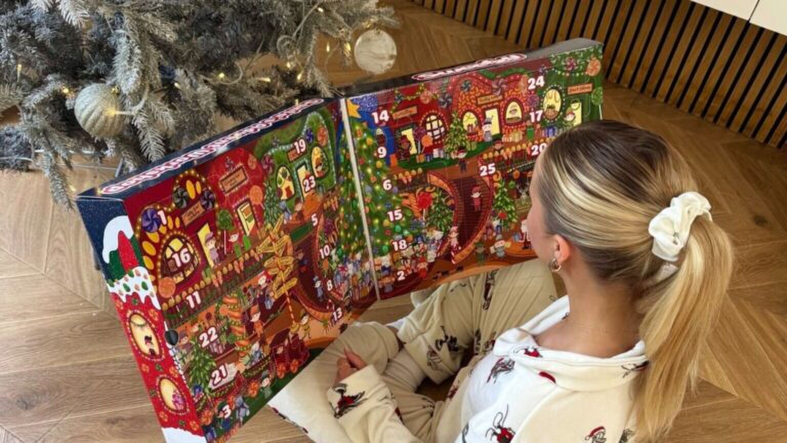 Vrouw opent adventskalender voor haar kerstboom.