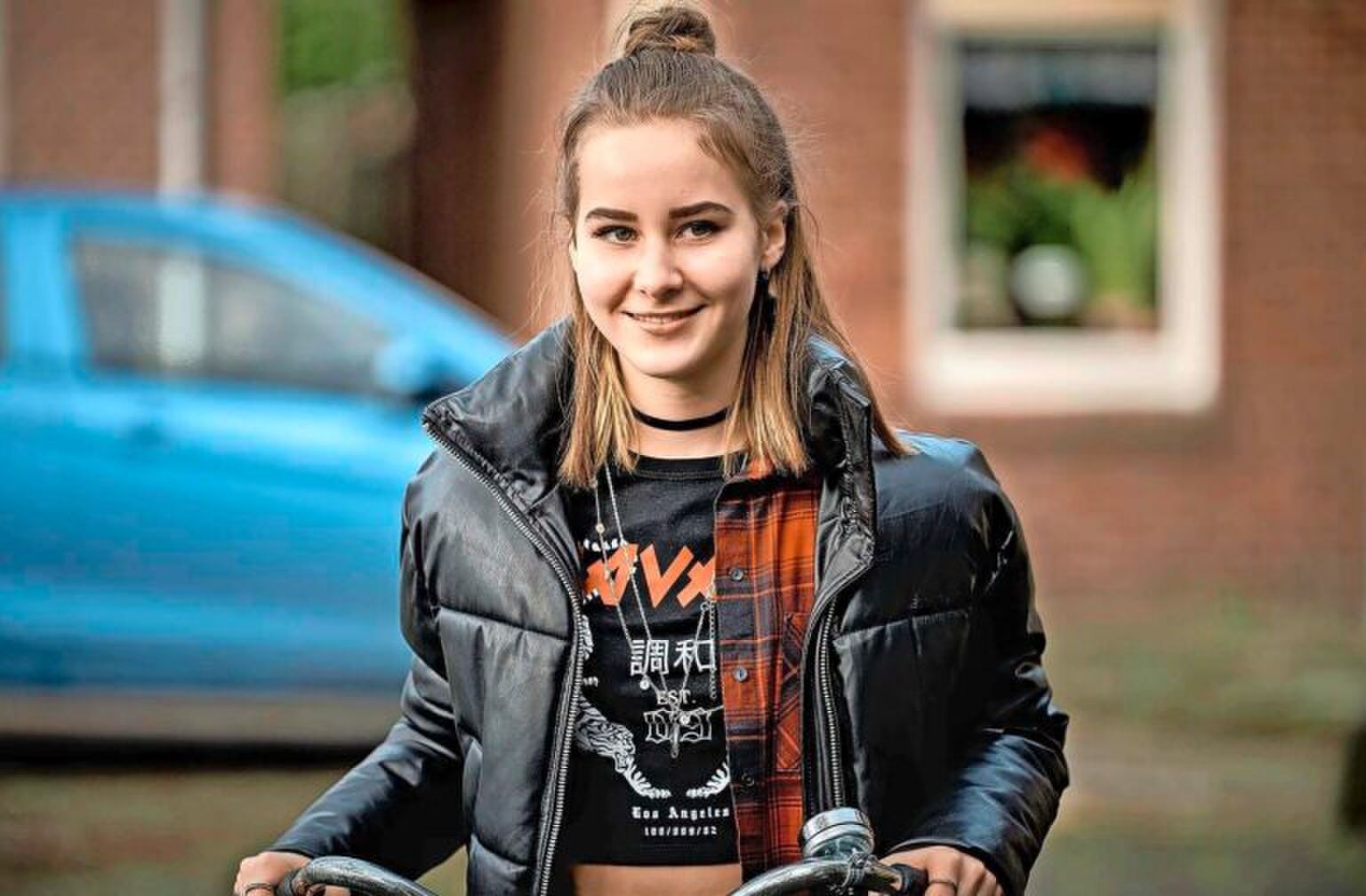 Meisje zit op een fiets, ze kijkt lachend voor zich uit. Sc&egrave;ne uit de serie Oogappels.