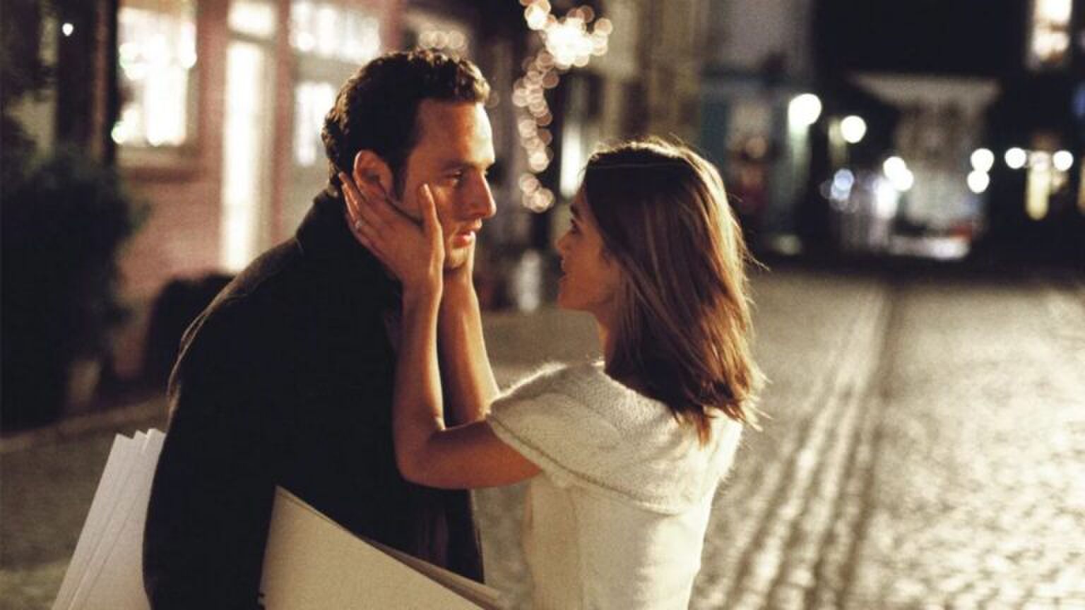 Twee personages uit de Love Actually film houden elkaar liefdevol vast. De vrouw vouwt haar handen om het gezicht van de man en kijkt hem diep in de ogen aan.