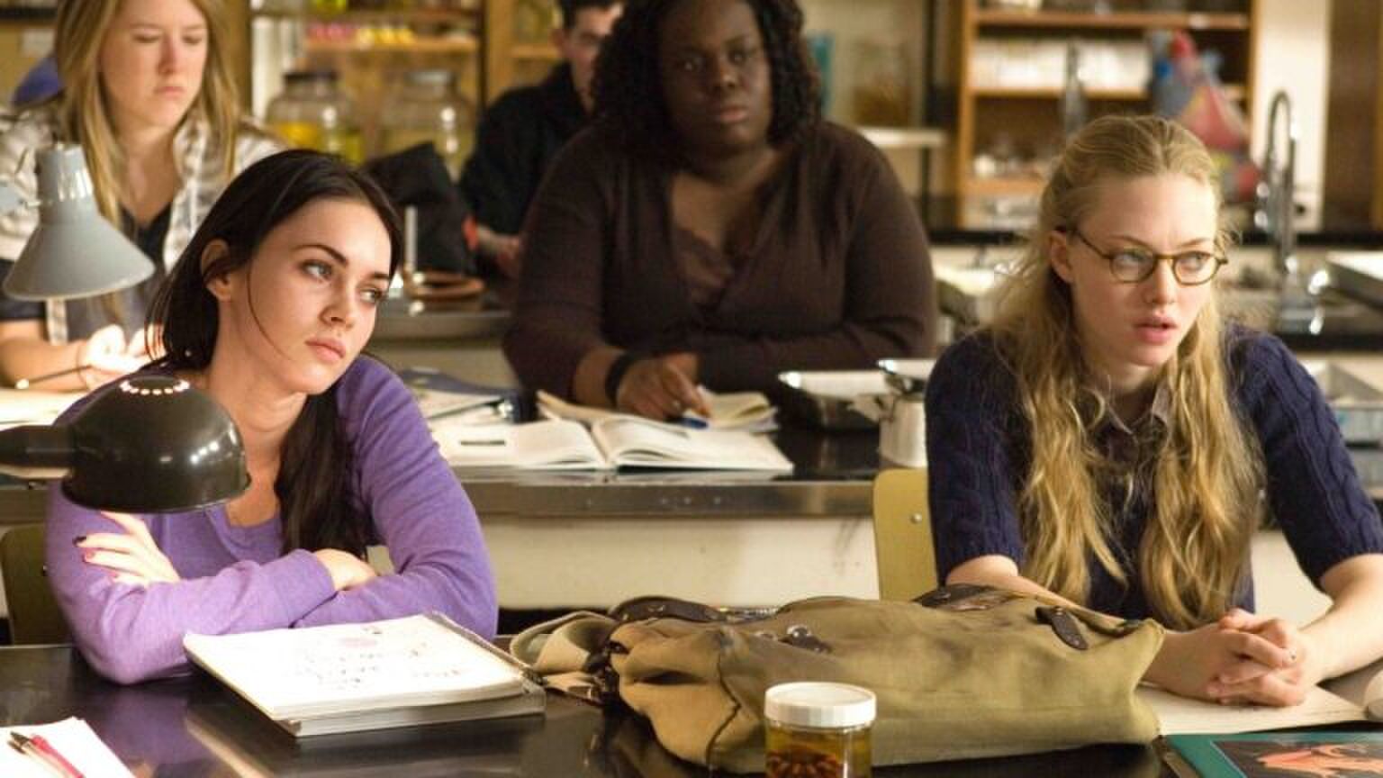 Twee meiden zitten in een klaslokaal. Ze kijken heel verveeld en vermoeid voor zich uit.