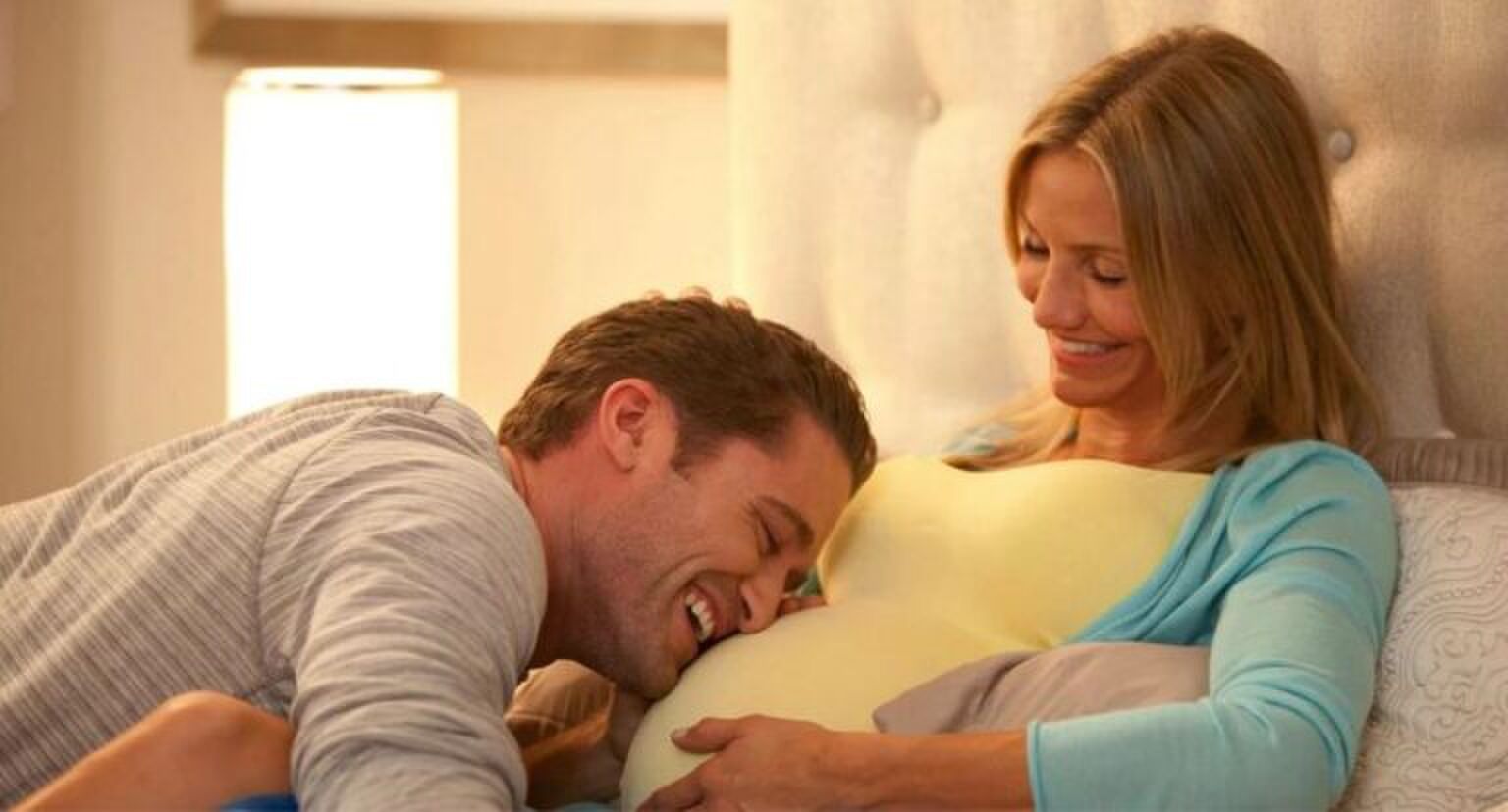 Man ligt op de zwangere buik van zijn vrouw.