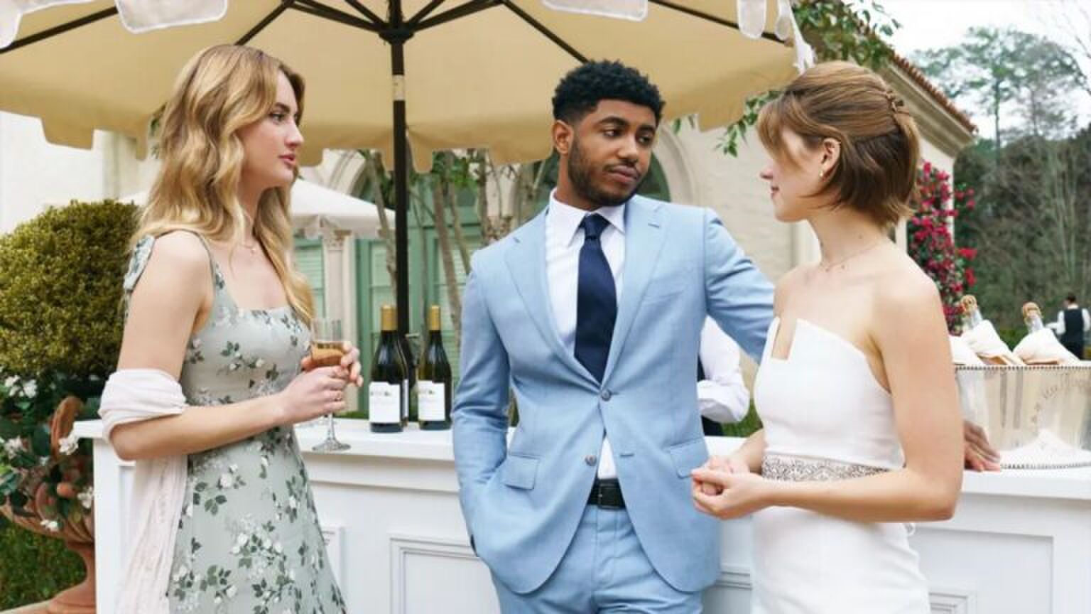 Een koppel kijkt liefdevol naar elkaar. Links van hen staat en vrouw aandoenlijk naar hen te kijken.