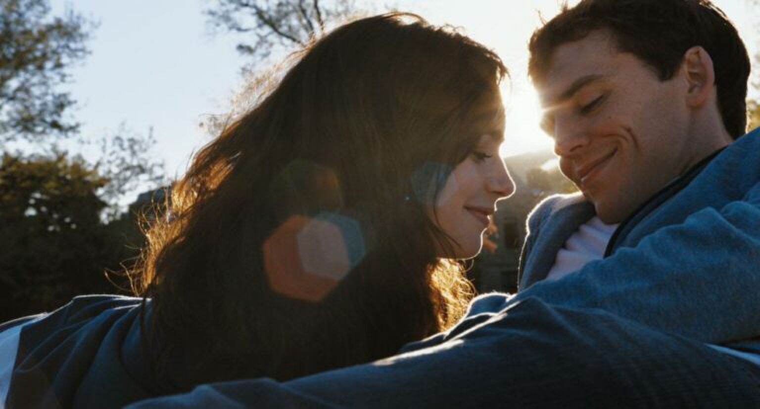 Een jongen en een meisje zitten dicht bij elkaar buiten.