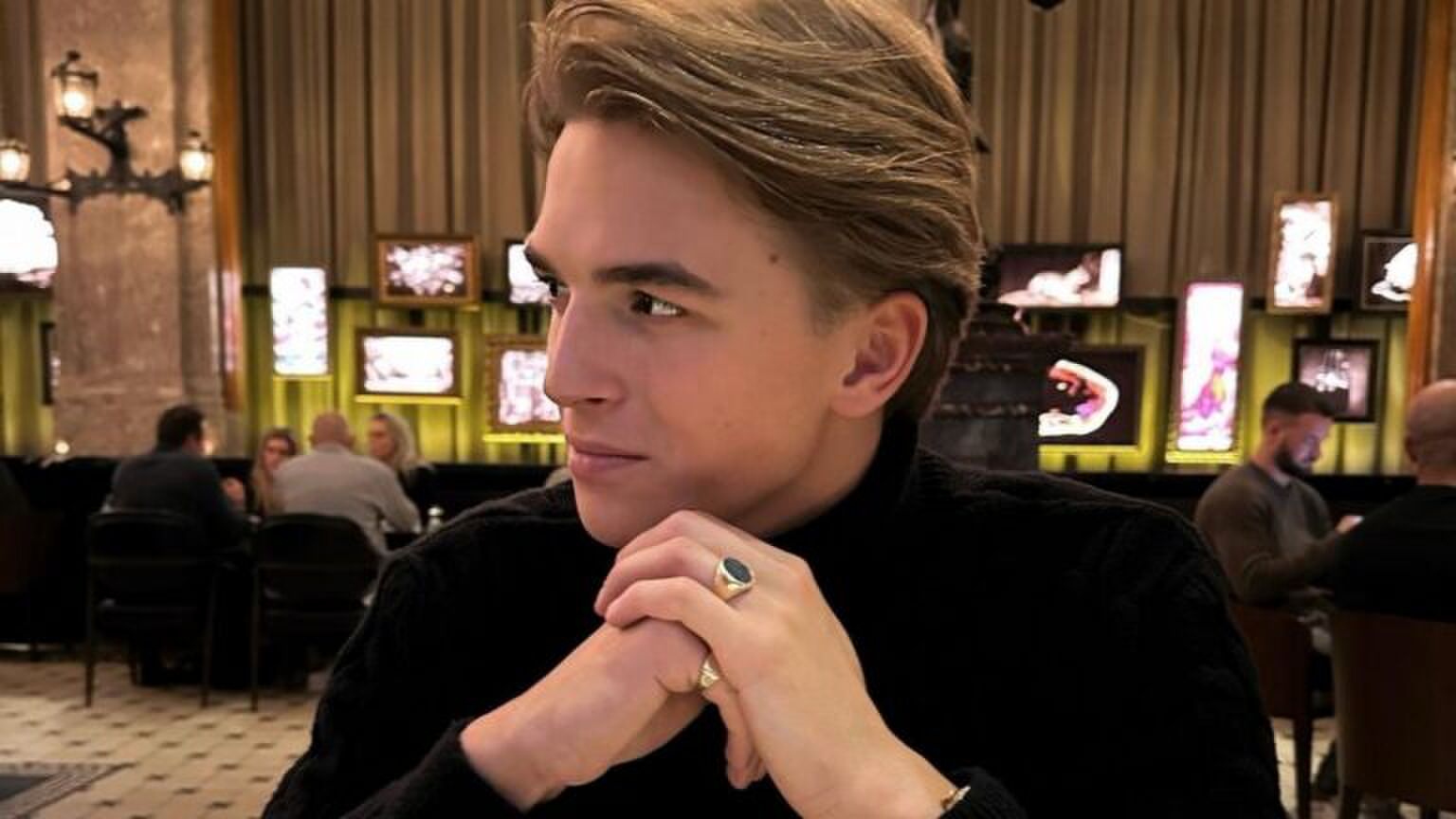 Foto van de zanger Antoon. Hij zit aan tafel en kijkt naar de zijkant. Hij houdt zijn handen gevouwen onder zijn kin.