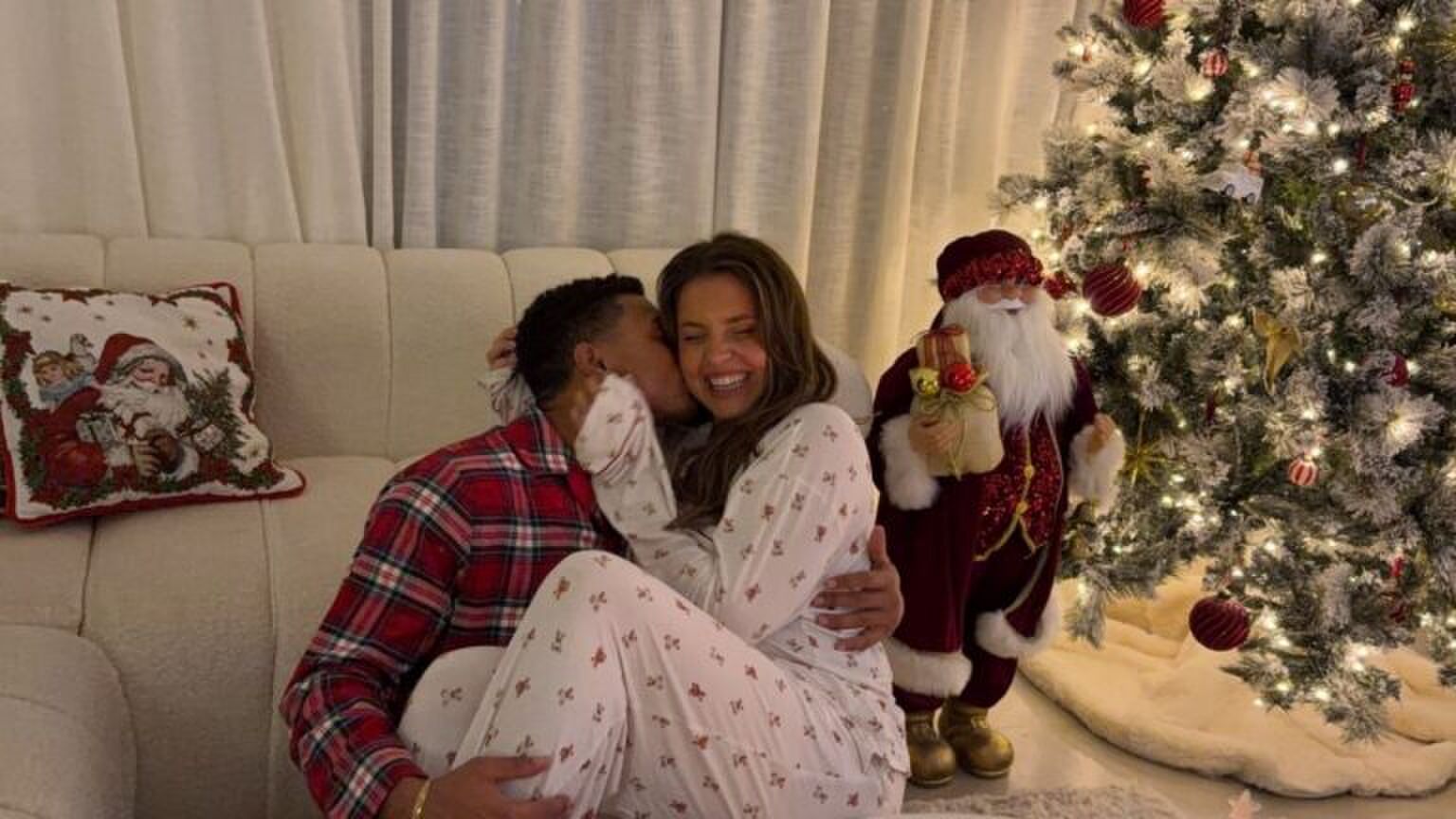 Man en vrouw knuffelen samen voor de kerstboom.