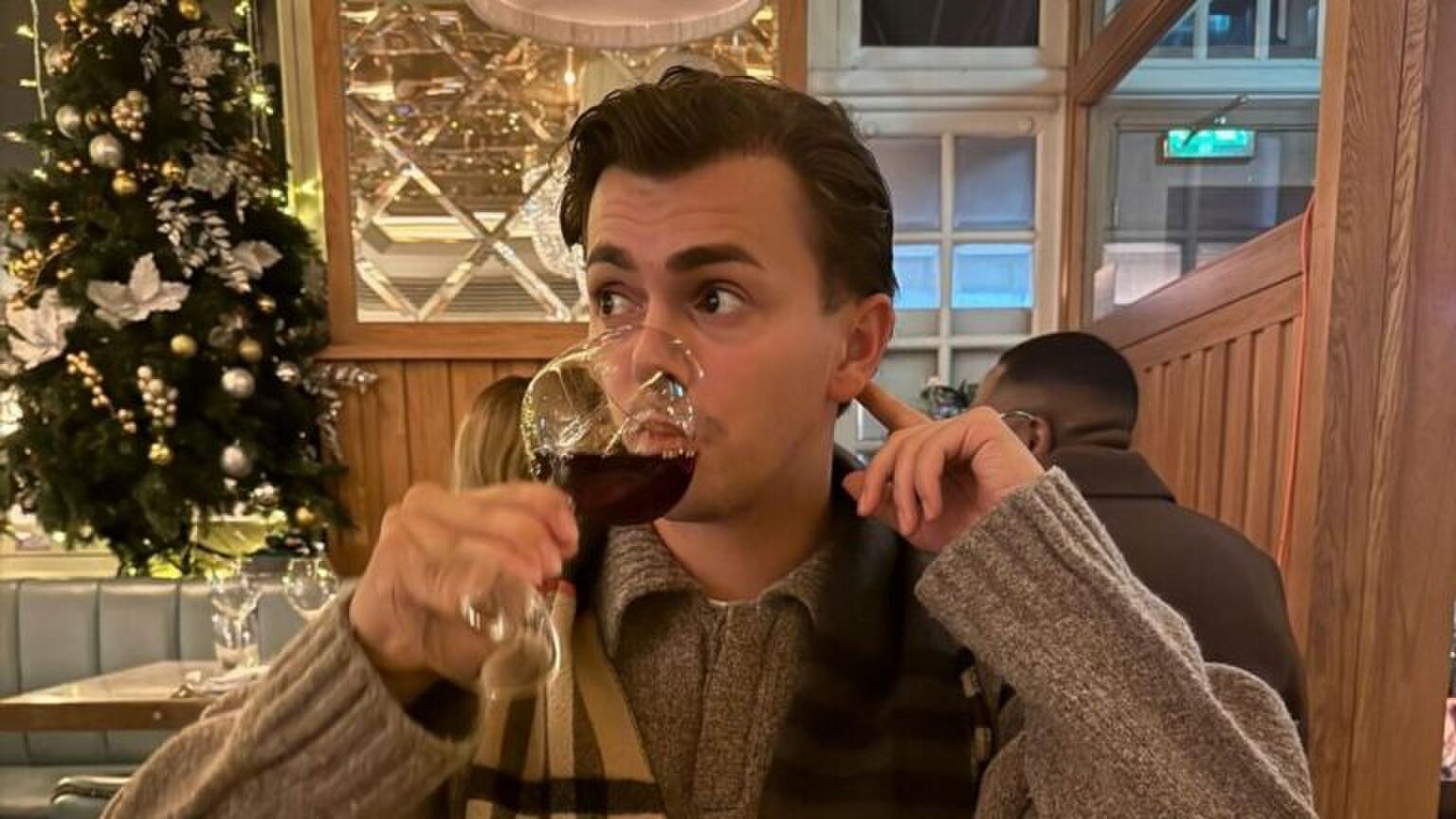 Foto van zanger Flemming. Hij kijkt opzij, terwijl hij een slok neemt van zijn glas rode wijn.