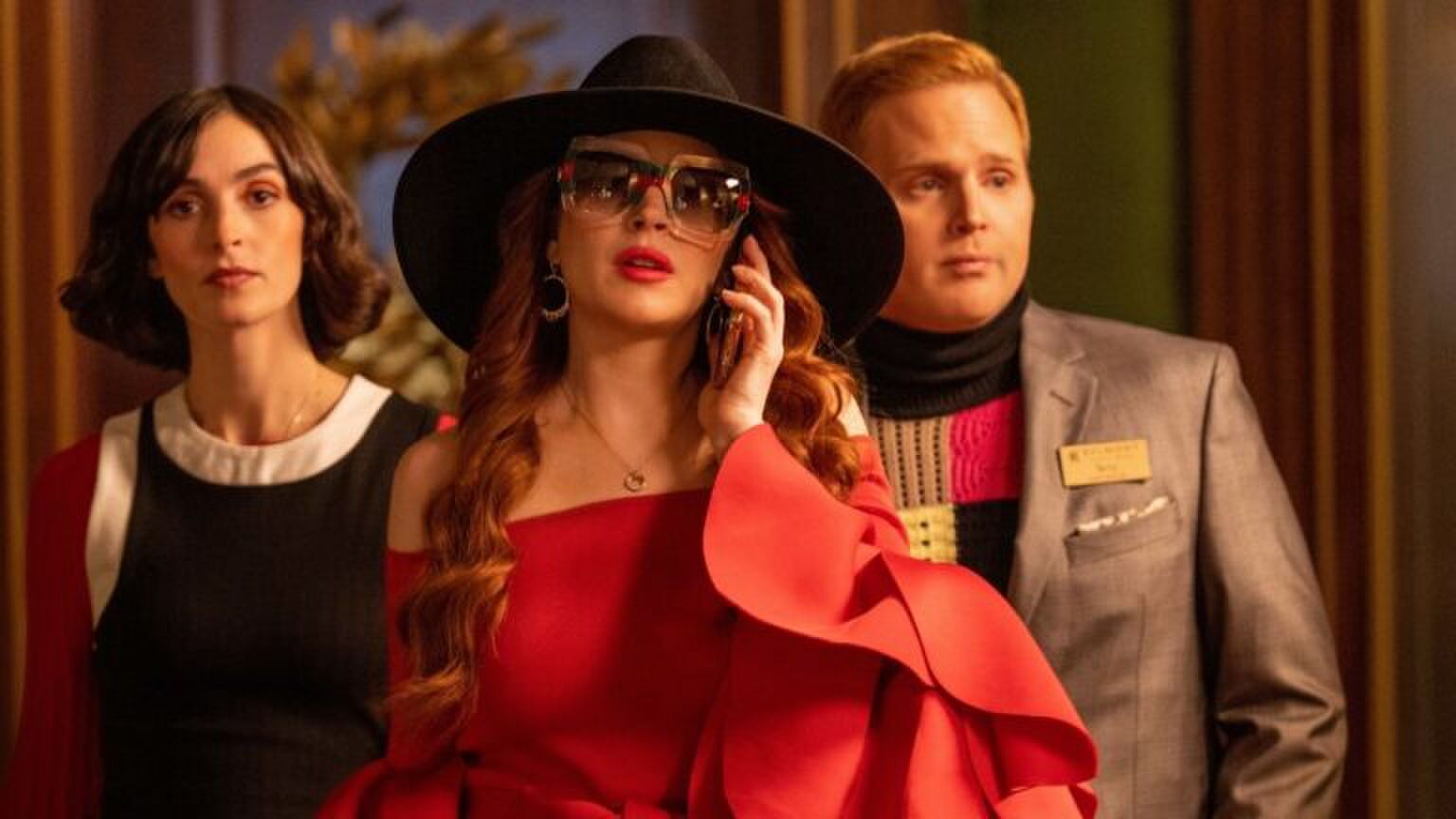 Een vrouw met een grote hoed en zonnebril aan de telefoon.