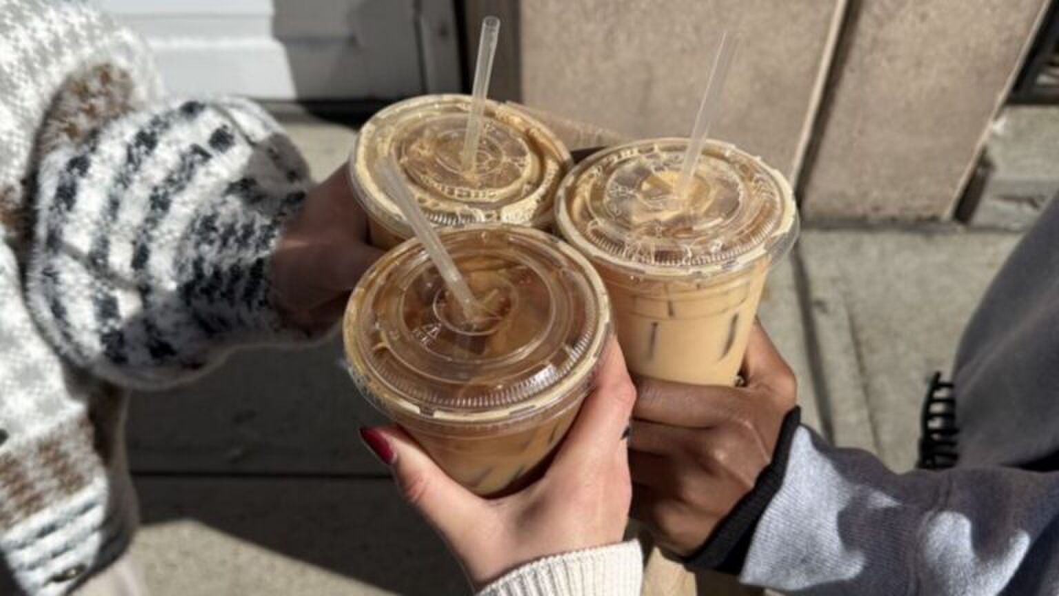 Drie meiden die koffiebekers vasthouden.