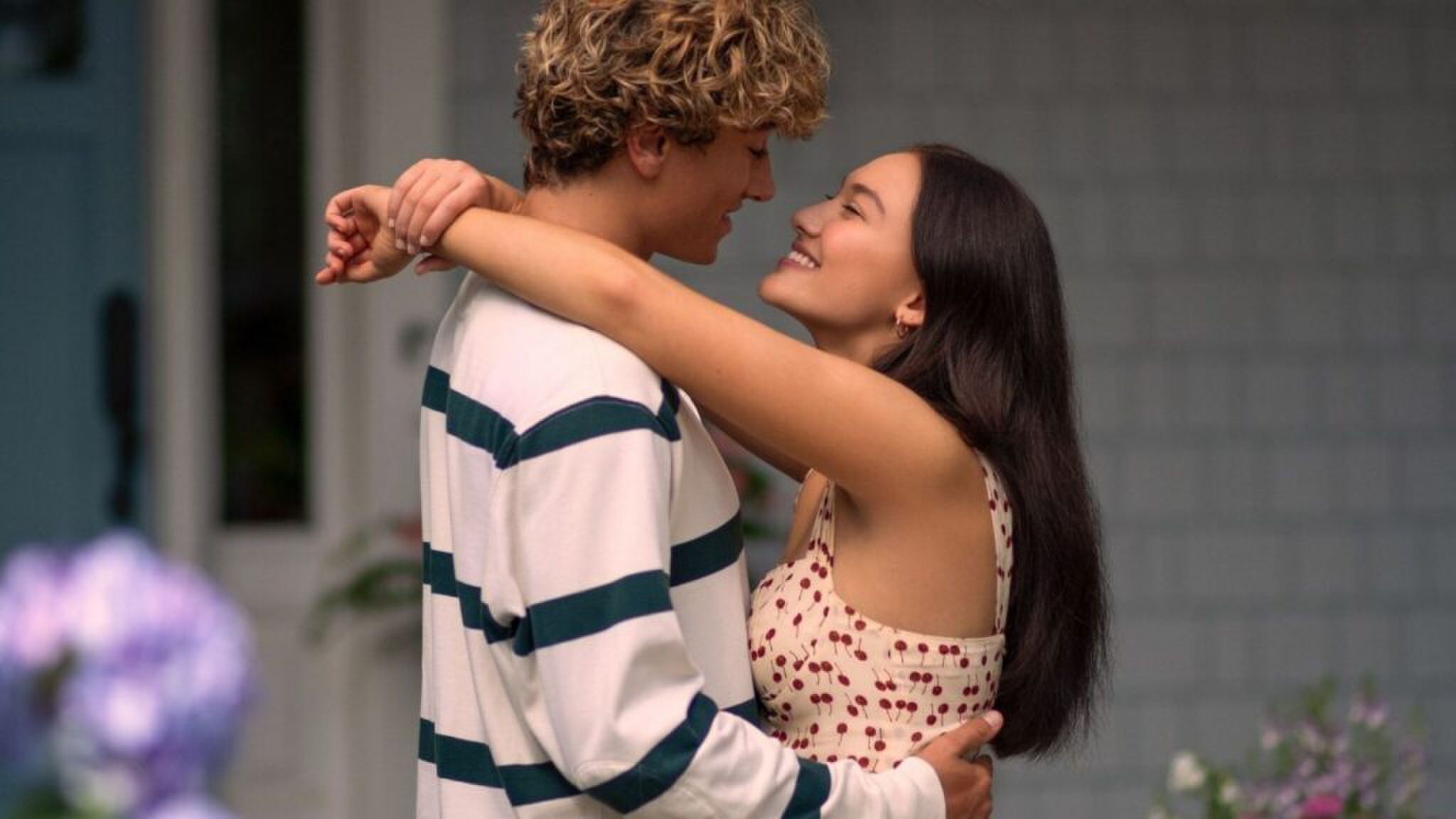 Meisje dat over jongen heen hangt met haar armen.