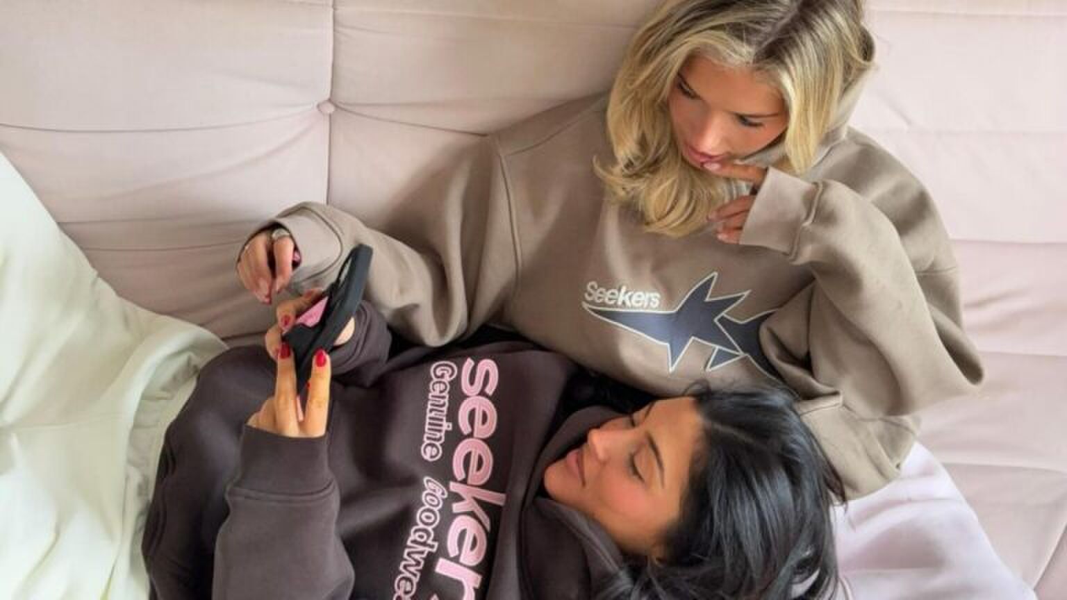 Twee vriendinnen liggen samen op de bank.