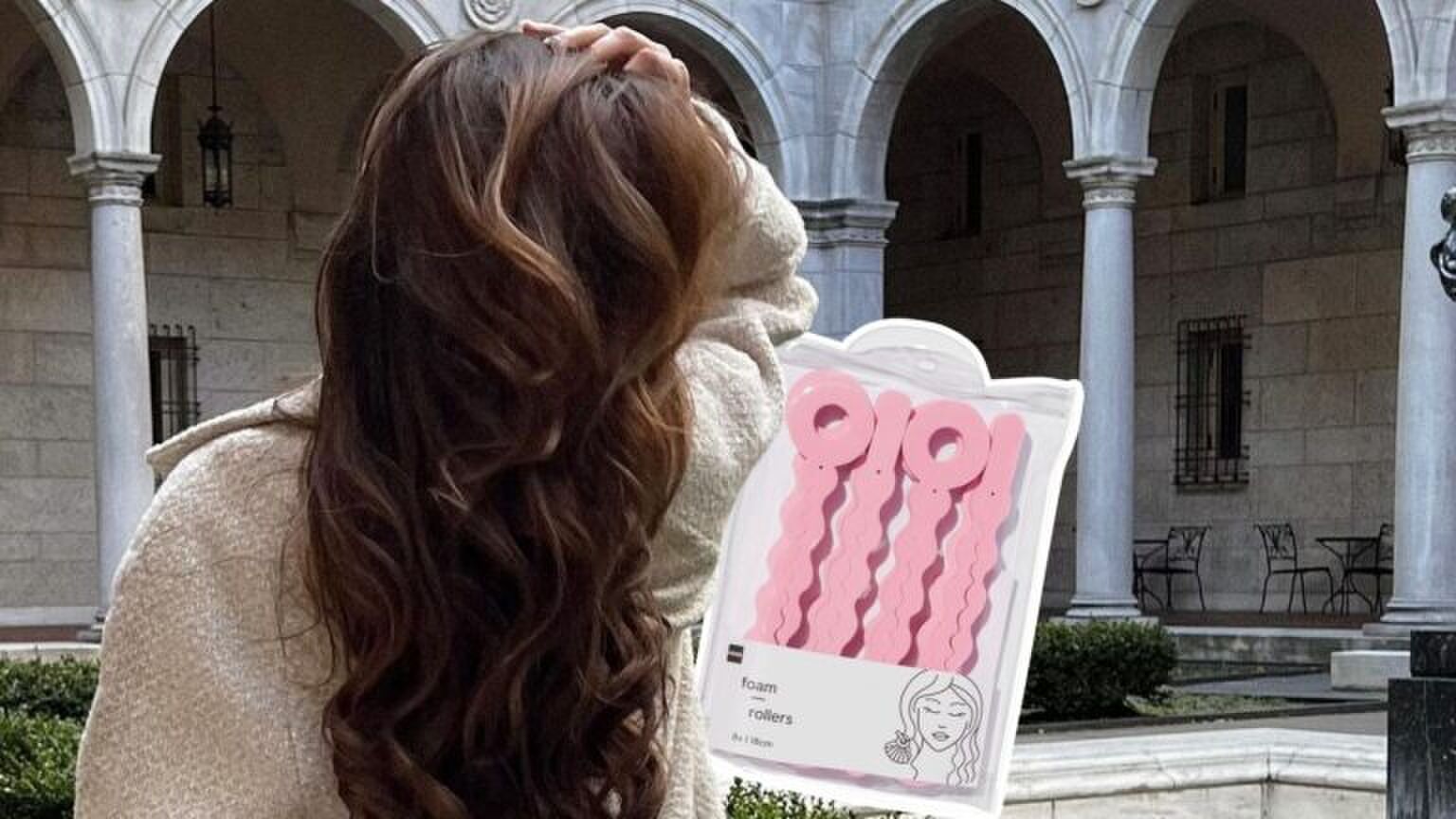 Iemand met gekruld haar poseert voor een foto.