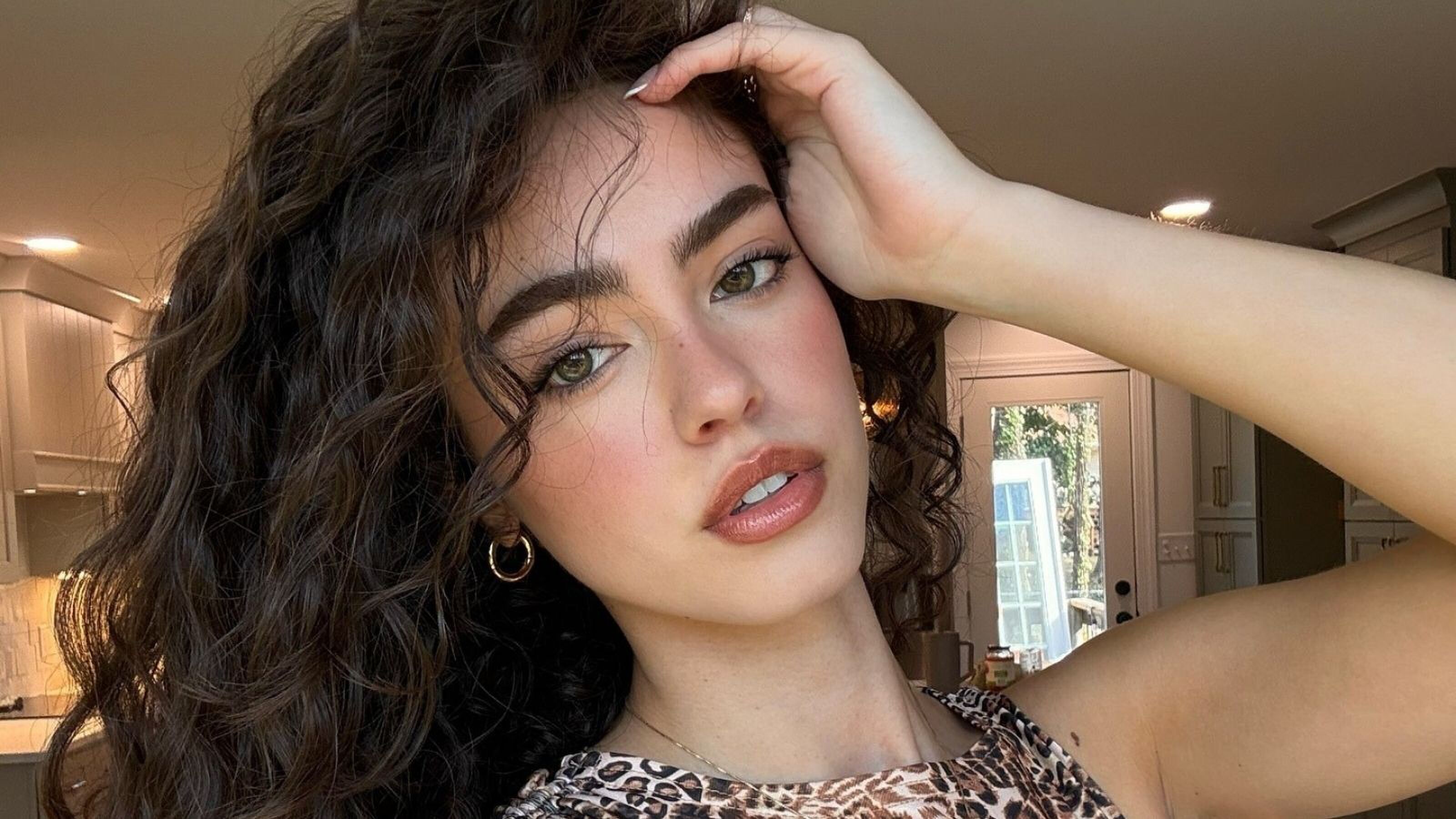 Foto van influencer Kiana Davis. Ze haalt een hand door haar krullende haar.