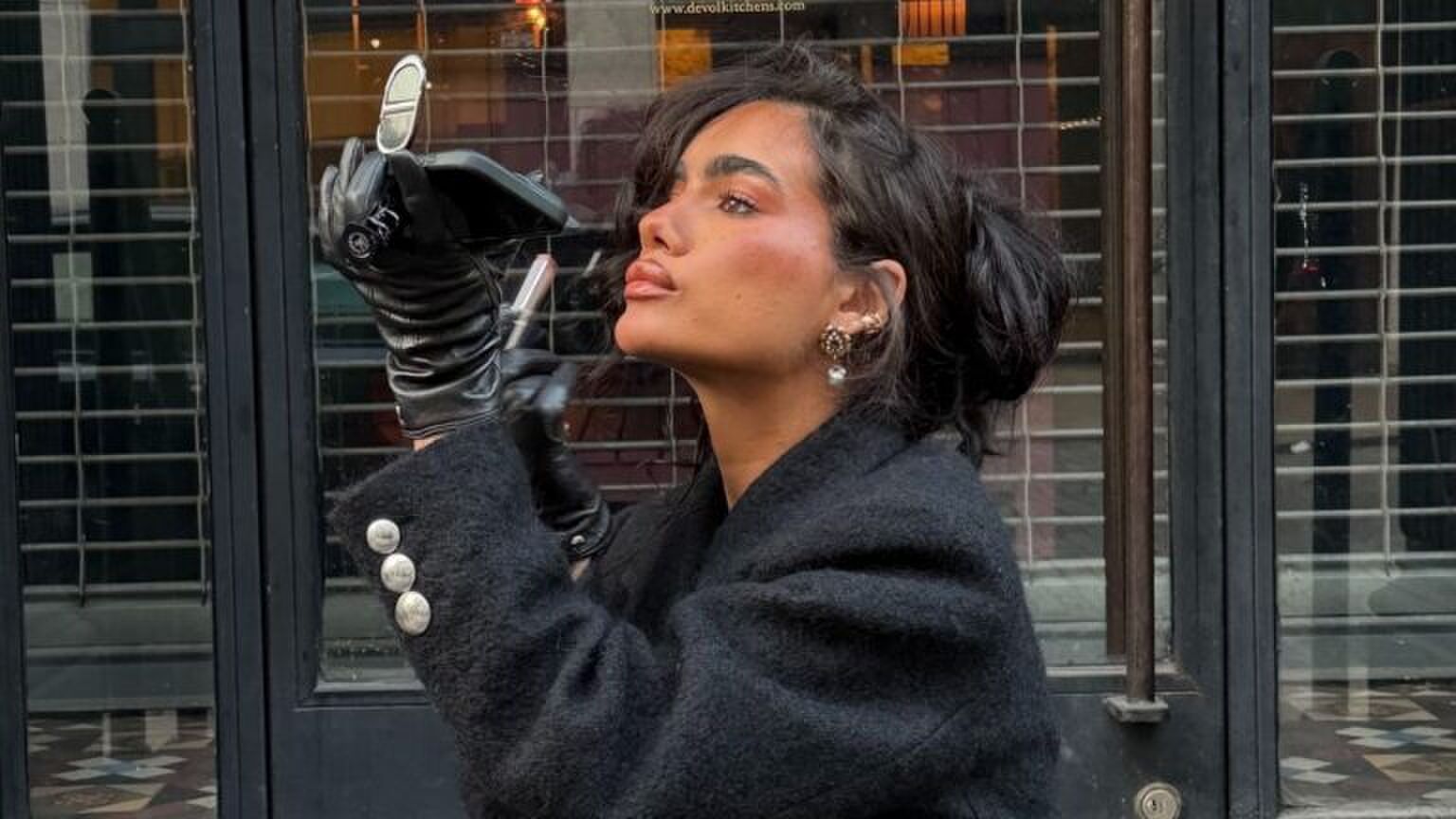 Foto van een vrouw die haar make-up bijwerkt in de spiegel.