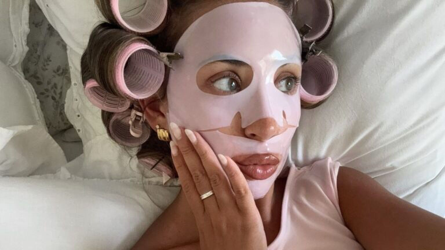 Foto van influencer Emma Sevilles. Ze heeft een roze gezichtsmasker op en krulspelden in haar haren.