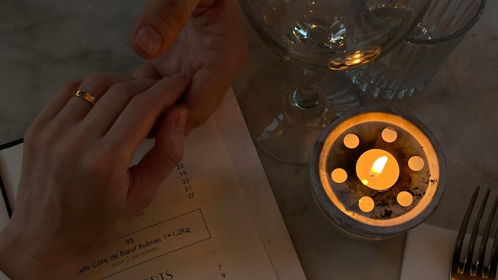 Twee mensen houden elkaars hand vast aan tafel.