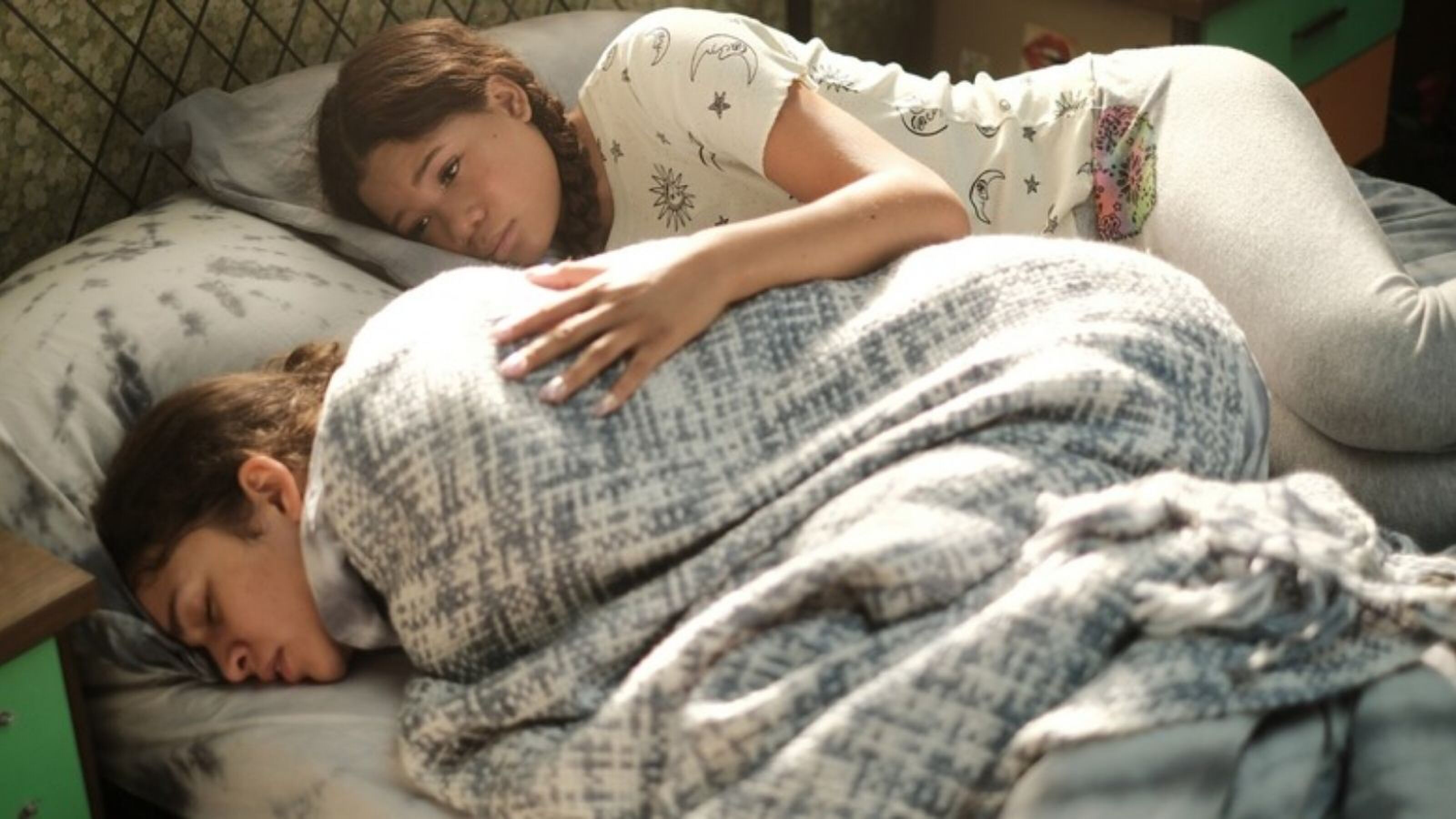 Sc&egrave;ne uit Euphoria. Twee meiden liggen op bed. De een heeft buikpijn, de ander troost haar.