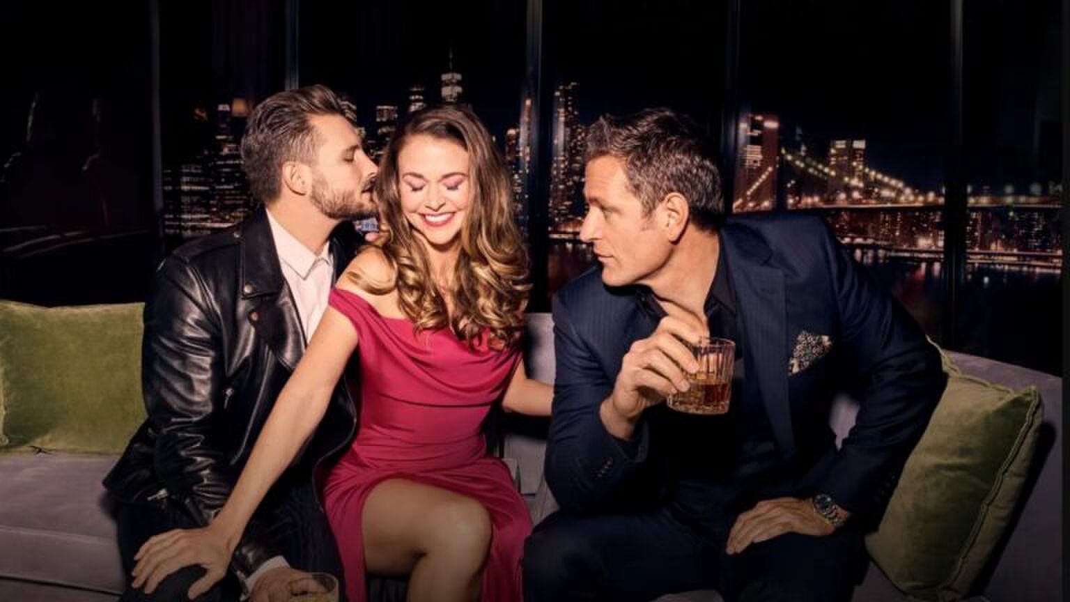 Een vrouw zit tussen twee mannen in. Ze kijken verliefd naar elkaar.
