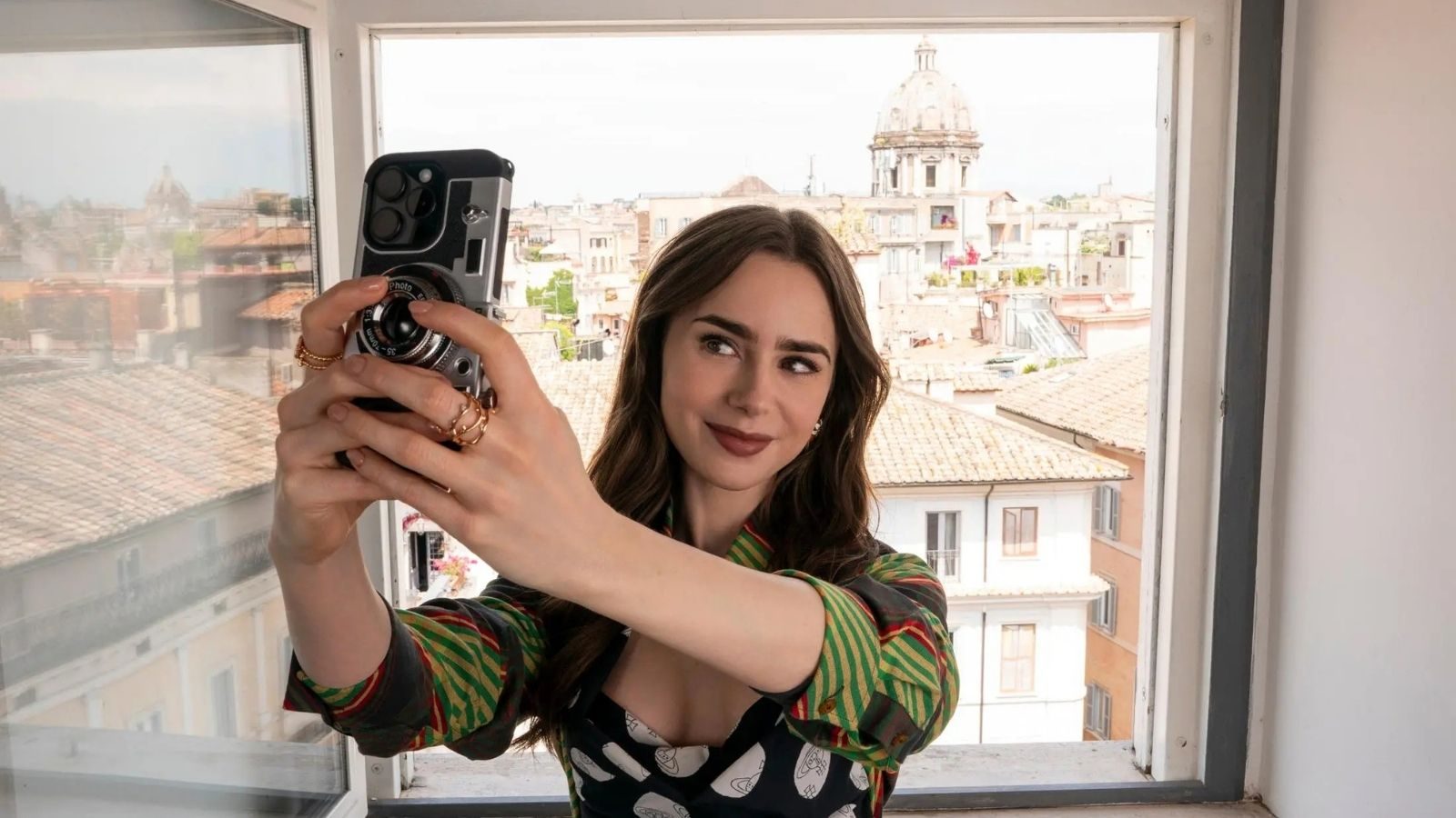 Lily Collins in de serie Emily in Paris. Ze neemt een selfie.
