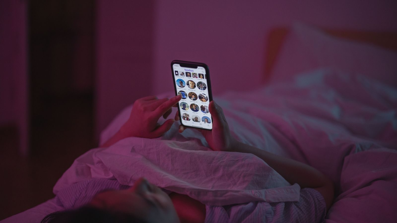 Iemand ligt in bed met zijn telefoon.