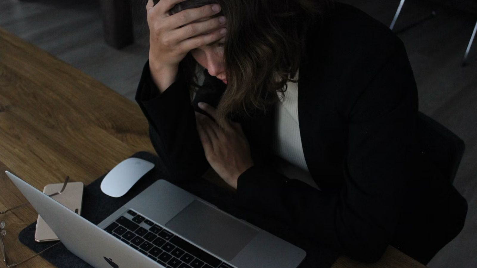 Vrouw die gestresst achter haar laptop zit.