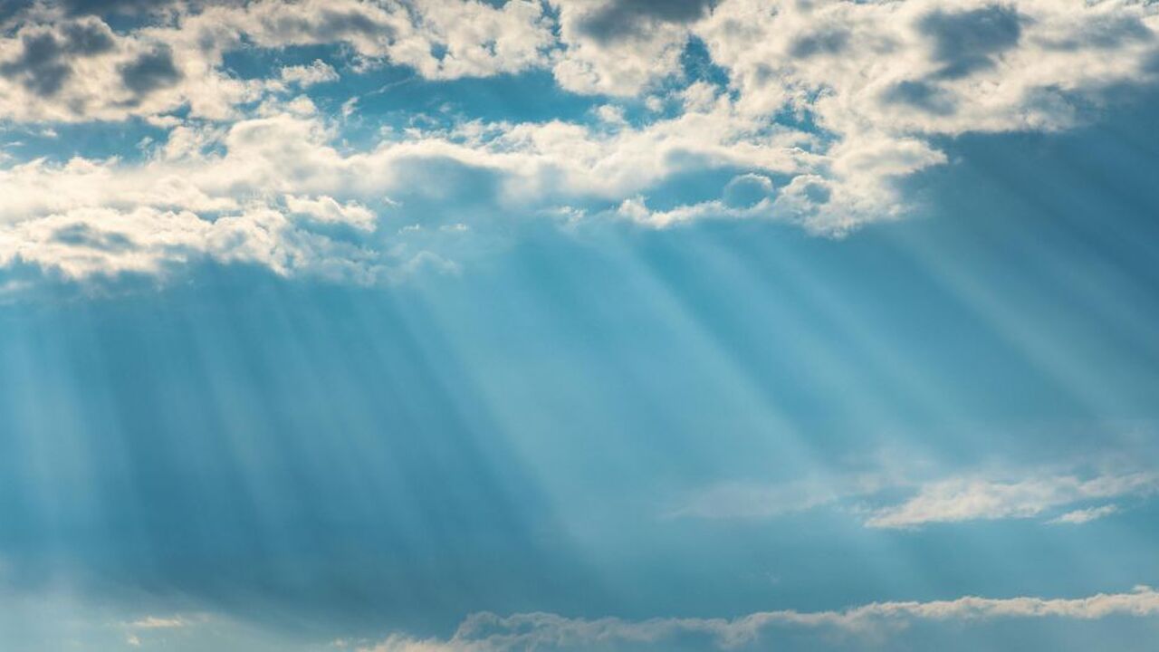 Het zonnetje schijnt door de wolken door.