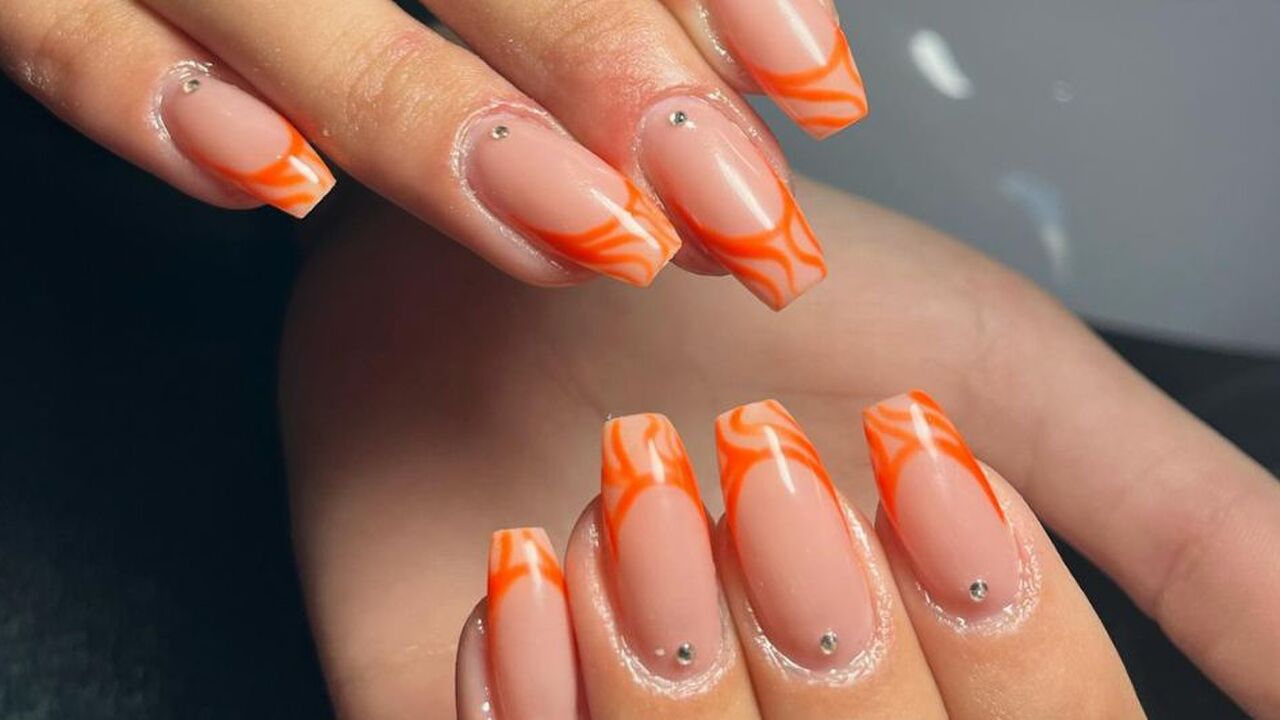 Twee handen met oranje nailart op de nagels.