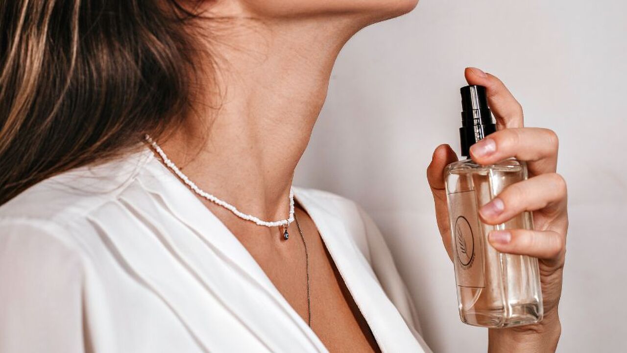 Een vrouw die parfum op spuit.