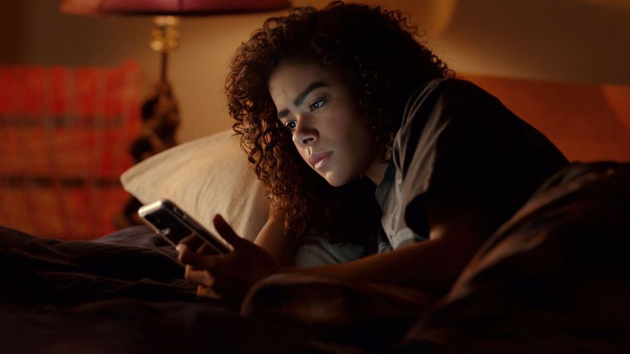 Scène uit Ginny & Georgia waar Ginny in bed ligt en op haar telefoon kijkt.