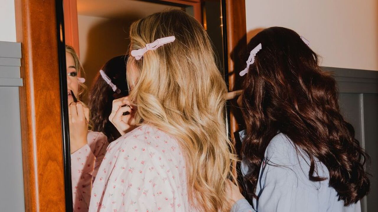 Twee vrouwen doen voor de spiegel hun make-up.