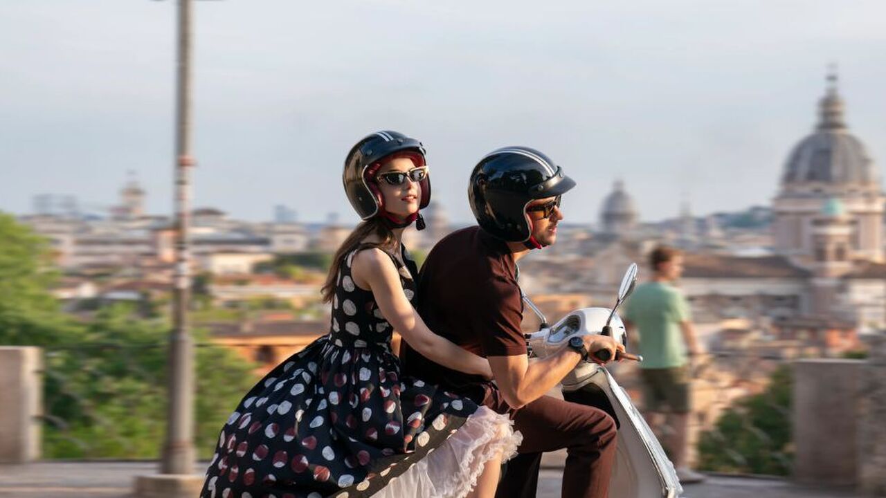 Scène uit Emily in Paris waar Emily achterop de scooter bij Marcello zit.