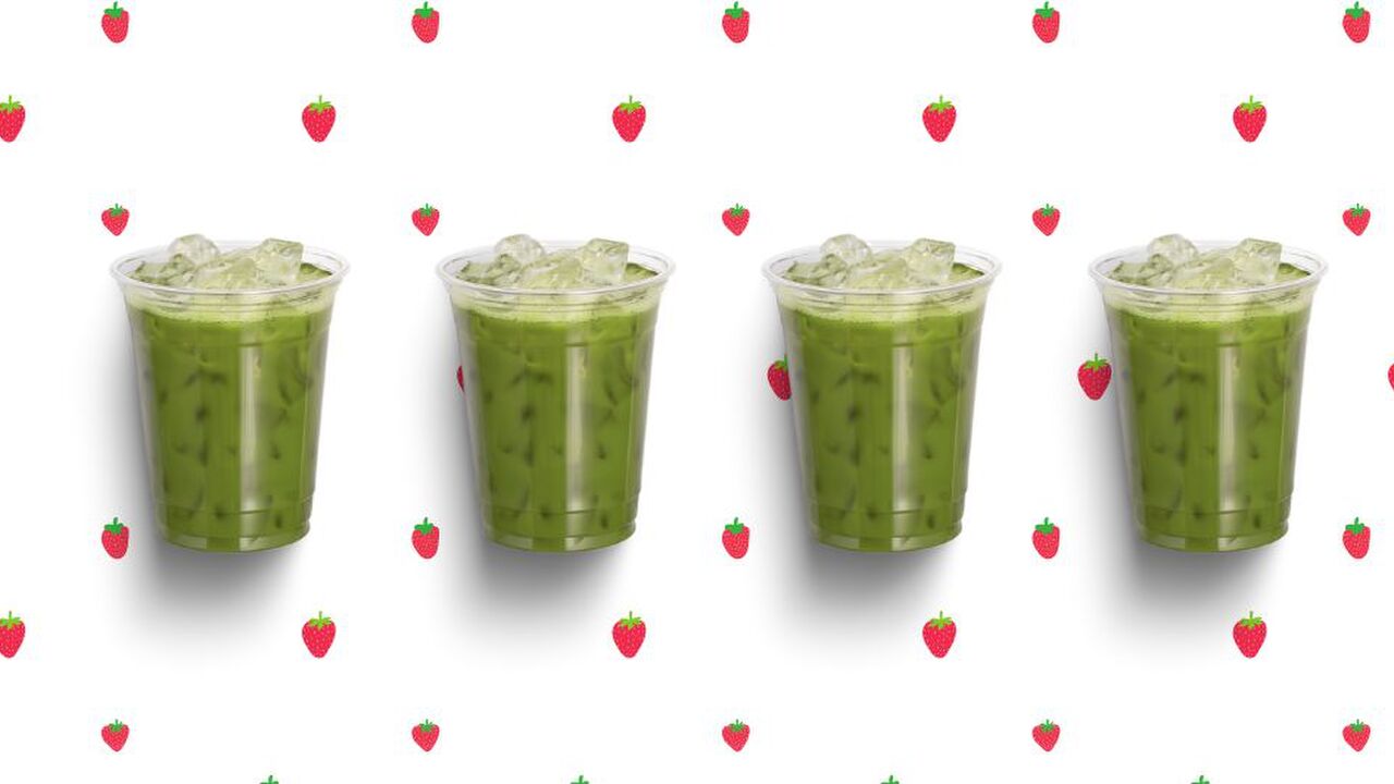 4 iced matcha's op een rijtje, op een aarbeien achtergrond.