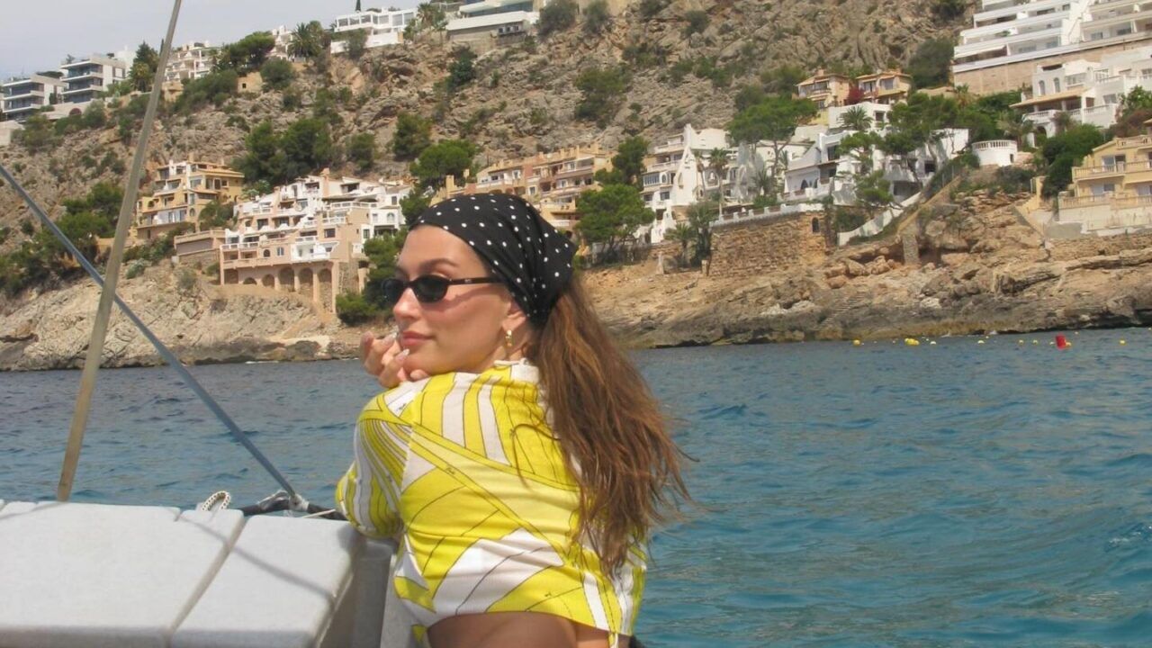 Hailey Bieber lacht naar de camera, terwijl ze op een boot vaart.