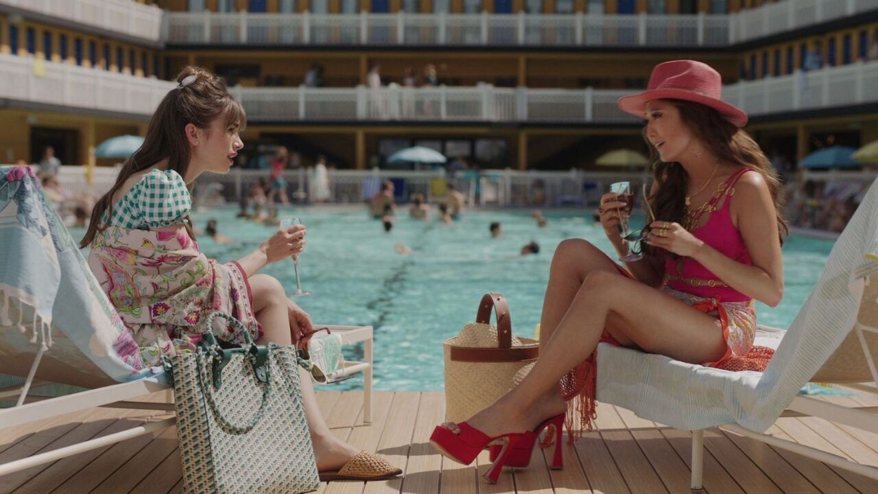 Twee vrouwen zitten aan het zwembad.
