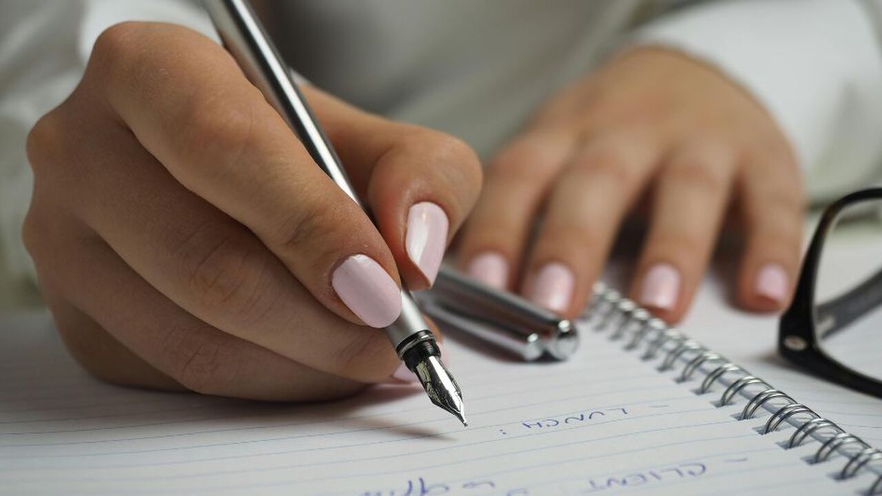 Vrouw schrijft op papier met pen.