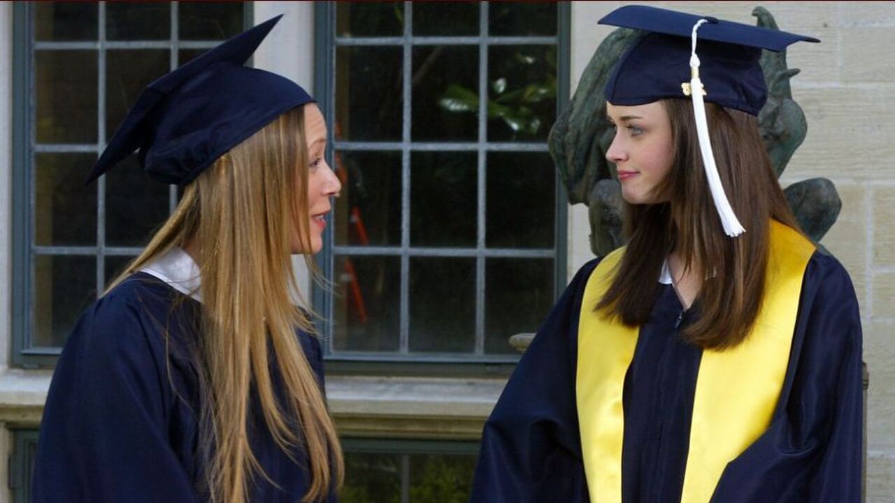 Twee vrouwen in cap and gown kijken elkaar aan.