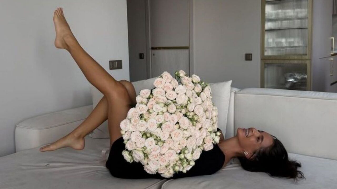 Meisje die met bloemen op een bank ligt.