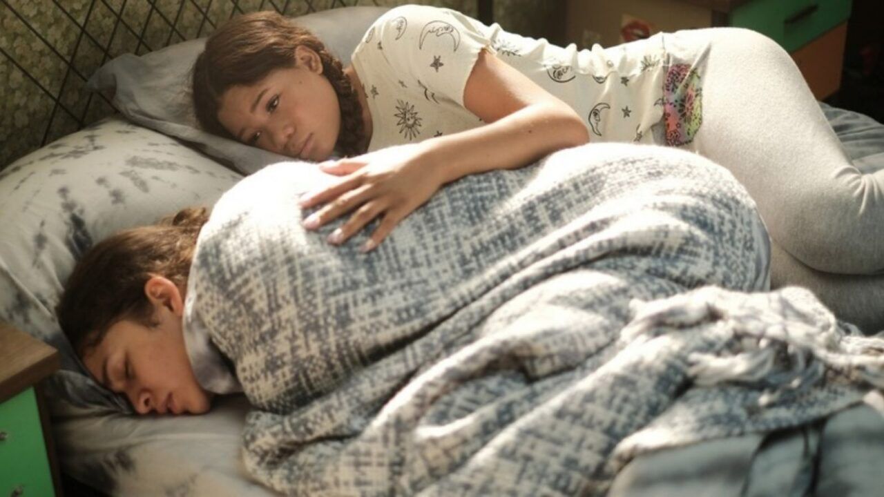 Sc&egrave;ne uit Euphoria. Twee meiden liggen op bed. De een heeft buikpijn, de ander troost haar.