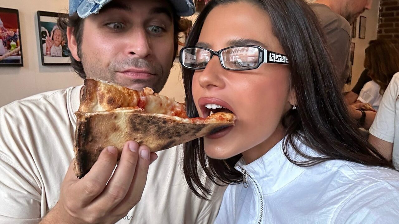 Man voert een stuk pizza een vrouw.