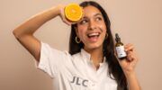 Jonge vrouw met een sinaasappel en een Vitamine C serum in haar handen.